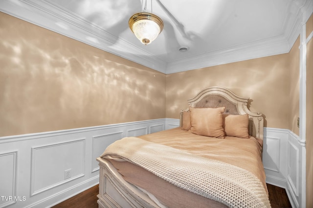 bedroom with dark wood-style flooring, a wainscoted wall, crown molding, and a decorative wall