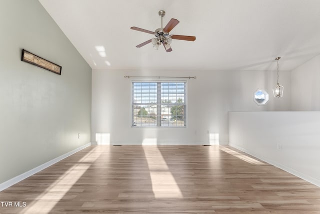 empty room featuring ceiling fan, vaulted ceiling, and light wood-type flooring