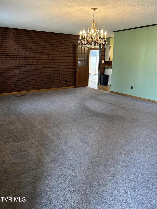 empty room featuring brick wall, carpet flooring, a textured ceiling, and a notable chandelier