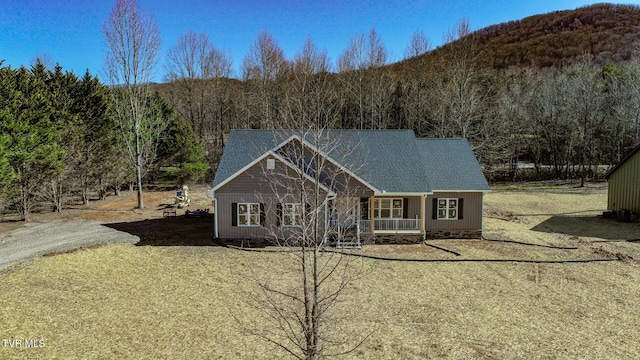 view of front facade with dirt driveway and a view of trees