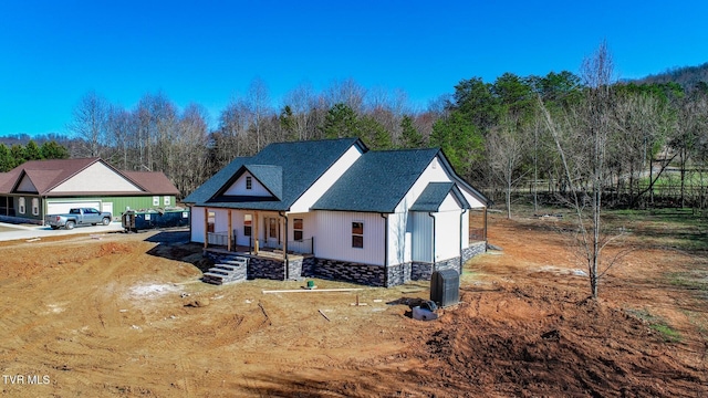 modern farmhouse style home with stone siding, a shingled roof, and a porch