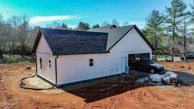 view of side of home featuring a shingled roof and a detached garage