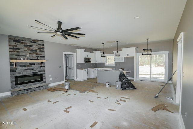 unfurnished living room with a ceiling fan, recessed lighting, a stone fireplace, and baseboards