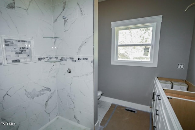 full bath with toilet, baseboards, and tiled shower