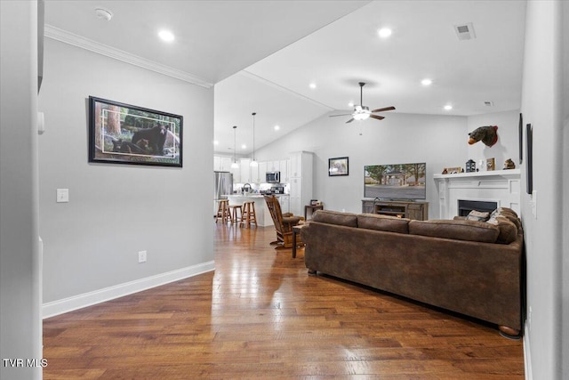 living room with dark hardwood / wood-style flooring, crown molding, vaulted ceiling, and ceiling fan