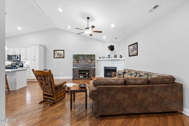 living room with ceiling fan, wood-type flooring, and vaulted ceiling