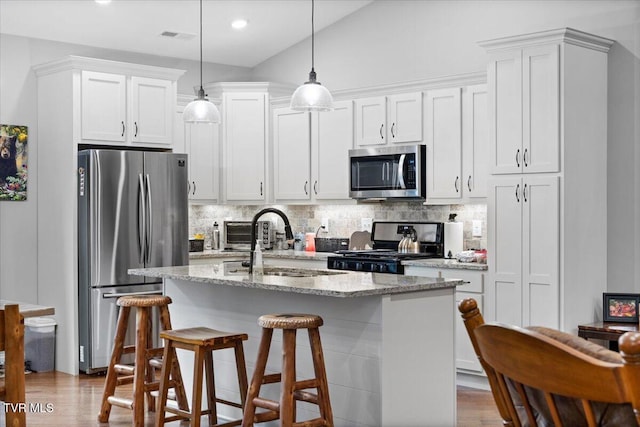 kitchen with sink, white cabinets, a kitchen island with sink, stainless steel appliances, and light stone countertops