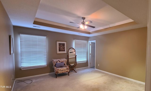 sitting room featuring a raised ceiling, plenty of natural light, light colored carpet, and ceiling fan