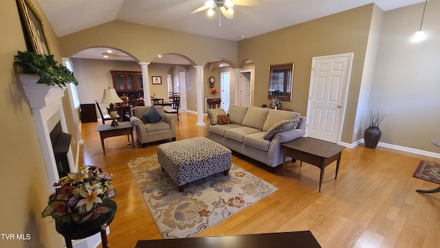 living room featuring lofted ceiling, light hardwood / wood-style floors, ceiling fan, and ornate columns