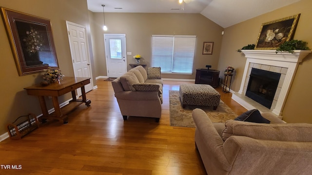 living room featuring hardwood / wood-style floors, vaulted ceiling, and a tile fireplace