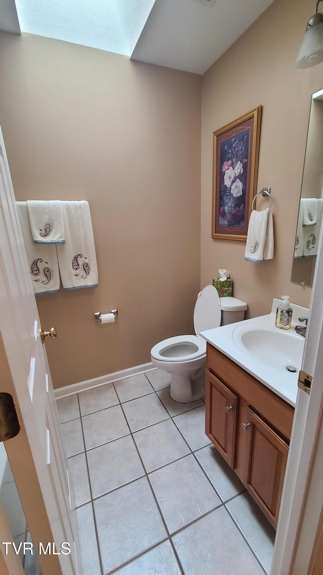 bathroom with tile patterned floors, toilet, a skylight, and vanity