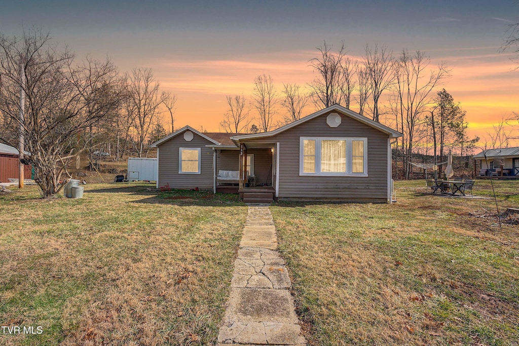 view of front of house featuring a fire pit, a lawn, and a porch