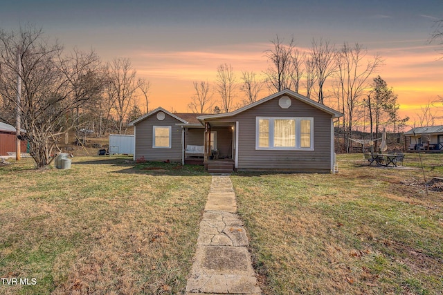 view of front of house featuring a fire pit, a lawn, and a porch