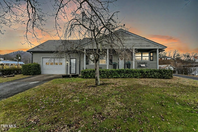 view of front of house featuring aphalt driveway, an attached garage, and a front lawn