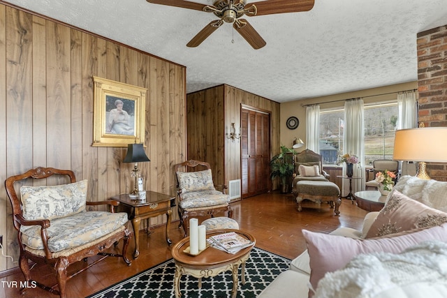 sitting room featuring ceiling fan, a textured ceiling, wood finished floors, and wood walls