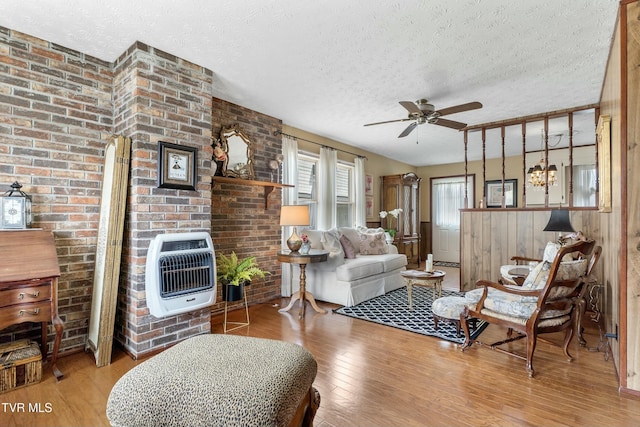 living area with wainscoting, hardwood / wood-style flooring, heating unit, a textured ceiling, and a ceiling fan