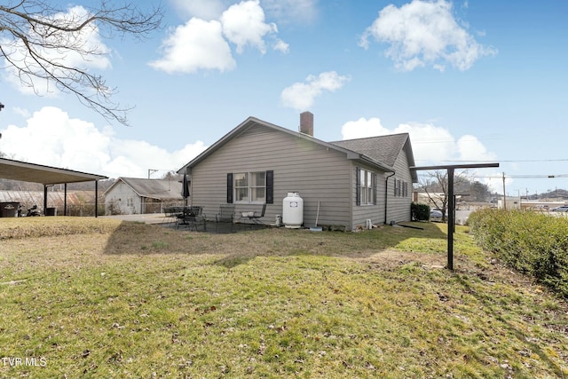 back of house with a yard, a patio, and a chimney