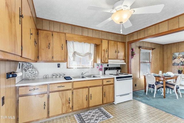 kitchen featuring a sink, light countertops, wooden walls, and white electric range oven