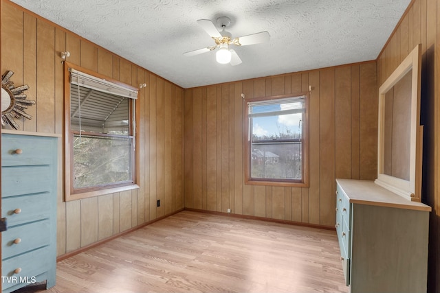 empty room with a ceiling fan, light wood finished floors, and a textured ceiling