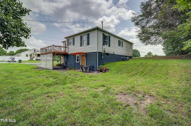 rear view of property with a wooden deck, a yard, and central air condition unit