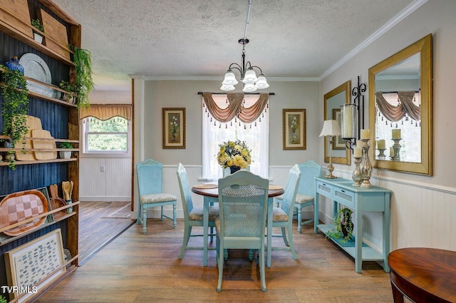 dining room with ornamental molding, hardwood / wood-style floors, a textured ceiling, and a chandelier