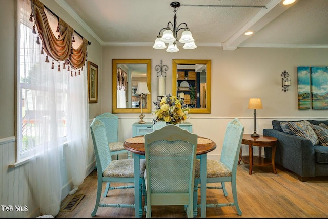 dining space with crown molding, an inviting chandelier, and light hardwood / wood-style flooring