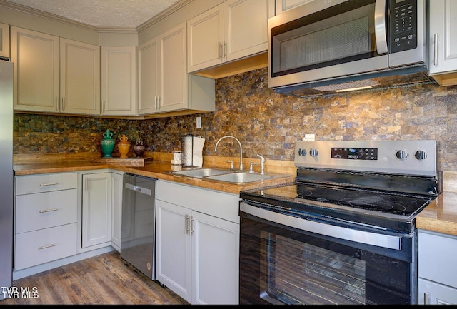 kitchen with sink, backsplash, stainless steel appliances, light hardwood / wood-style floors, and a textured ceiling