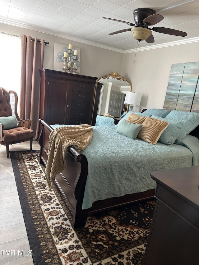 bedroom with ornamental molding, hardwood / wood-style floors, and ceiling fan