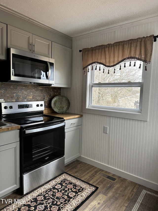 kitchen featuring crown molding, dark wood-type flooring, gray cabinets, stainless steel appliances, and a textured ceiling