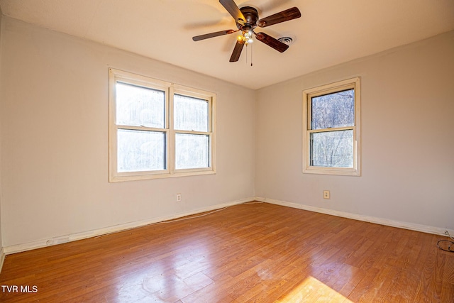 spare room with ceiling fan, wood-type flooring, and a healthy amount of sunlight