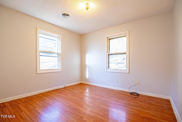 spare room featuring a textured ceiling and light hardwood / wood-style flooring