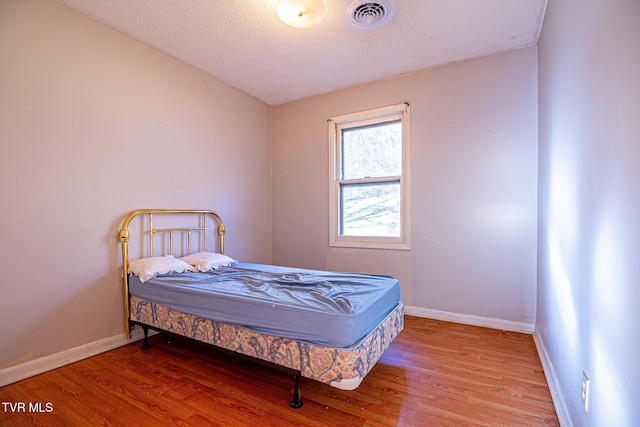 bedroom featuring hardwood / wood-style flooring and a textured ceiling