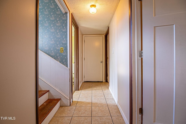 hall with light tile patterned floors and a textured ceiling