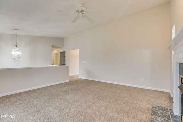 unfurnished living room featuring ceiling fan with notable chandelier, vaulted ceiling, and carpet flooring