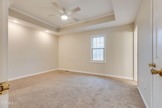 spare room with ceiling fan, ornamental molding, a tray ceiling, and carpet