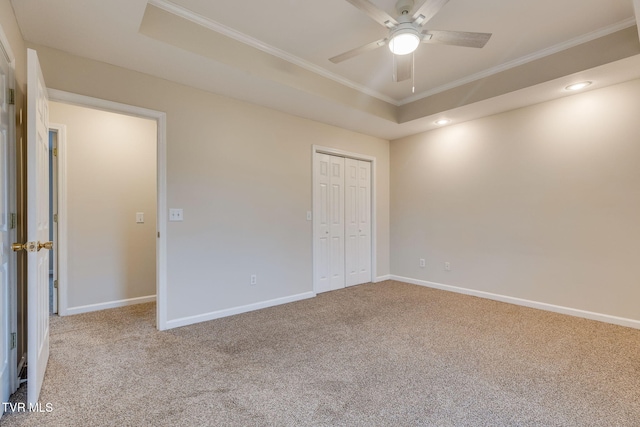 unfurnished bedroom featuring crown molding, carpet flooring, a closet, and a tray ceiling