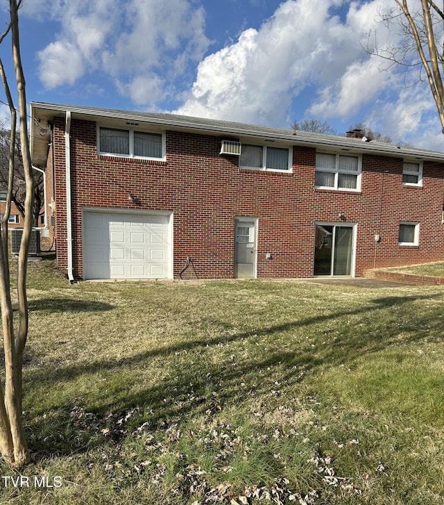 rear view of property featuring a garage and a lawn