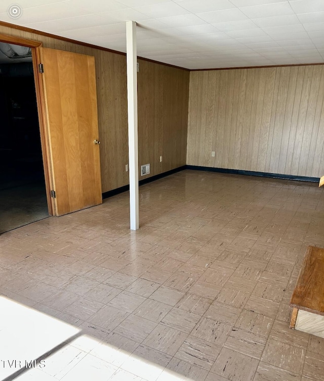 basement with wooden walls and ornamental molding