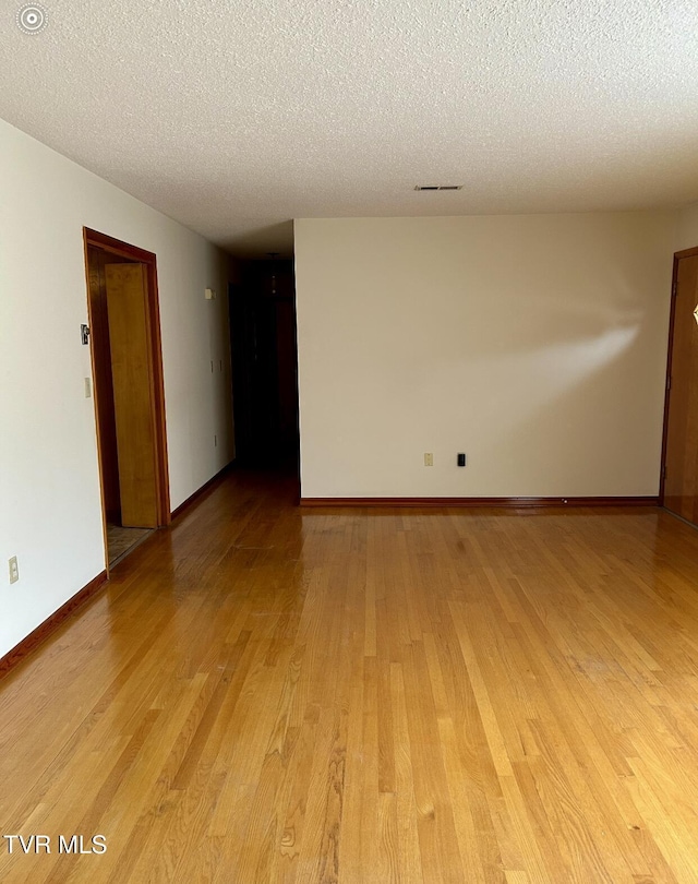 unfurnished room featuring light hardwood / wood-style flooring and a textured ceiling