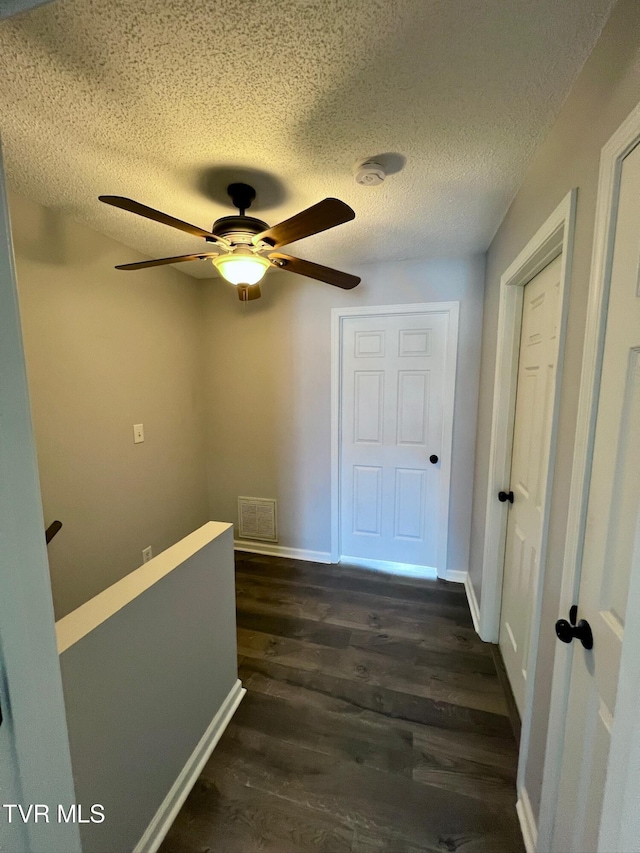 corridor featuring dark wood-type flooring and a textured ceiling