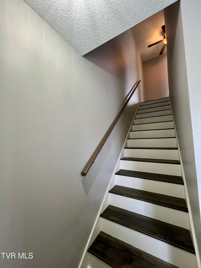 staircase featuring ceiling fan and a textured ceiling