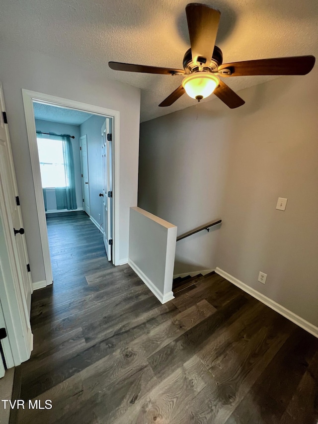 corridor with dark wood-type flooring and a textured ceiling