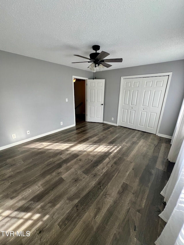 unfurnished bedroom featuring ceiling fan, a textured ceiling, dark hardwood / wood-style flooring, and a closet