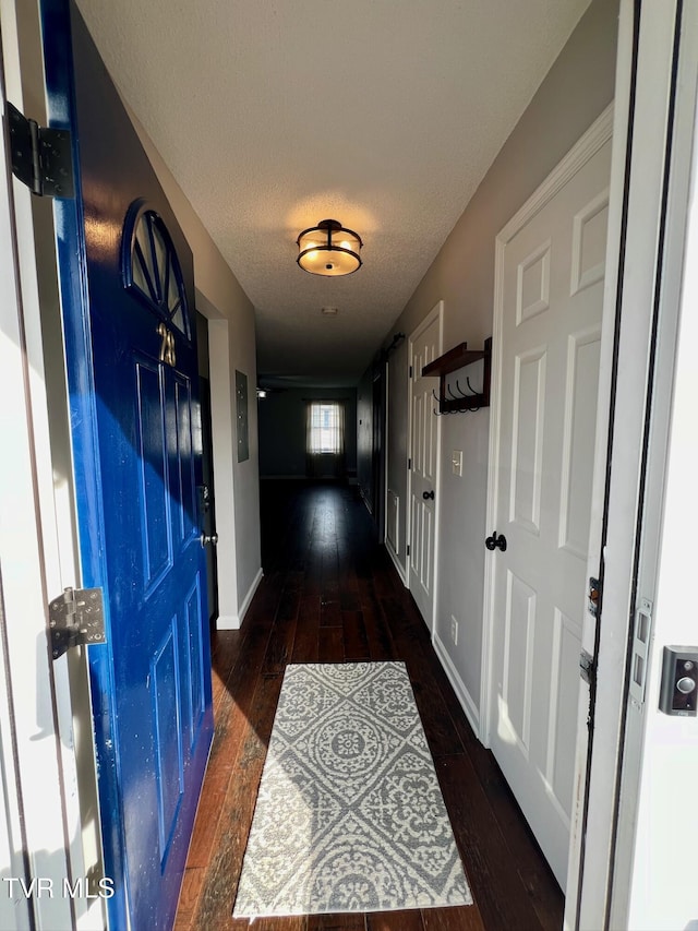 hallway with dark hardwood / wood-style floors and a textured ceiling