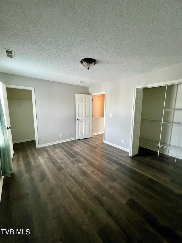 unfurnished bedroom with a closet, dark hardwood / wood-style floors, and a textured ceiling