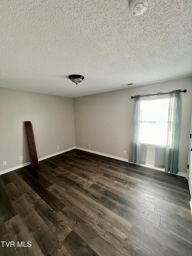 empty room featuring a textured ceiling and dark hardwood / wood-style flooring