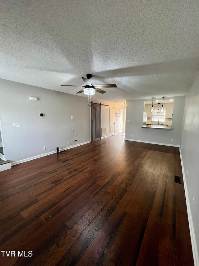 unfurnished living room with ceiling fan, dark hardwood / wood-style flooring, and a textured ceiling