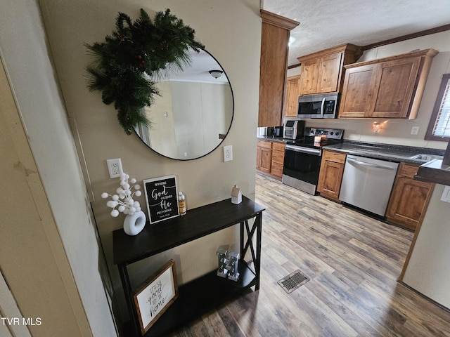 kitchen with stainless steel appliances, a textured ceiling, and light wood-type flooring