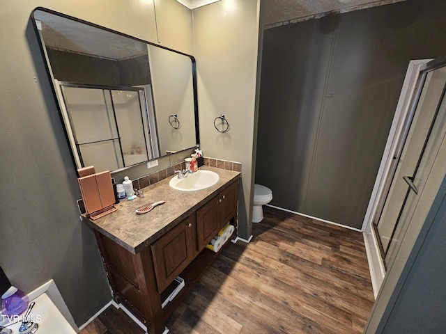 bathroom with wood-type flooring, toilet, vanity, and walk in shower