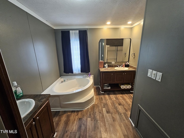 bathroom featuring vanity, hardwood / wood-style floors, a washtub, and a textured ceiling